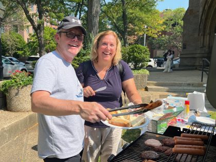 Man and woman cooking on a grill and smiling