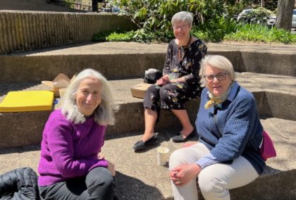 Three women sitting outside on steps smiling outside 
