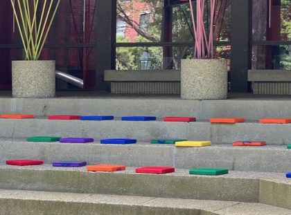 Brightly colored cushions sitting on concrete steps outside a building. 