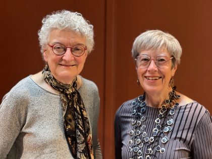 Two women with short grey hair and wearing glasses smiling