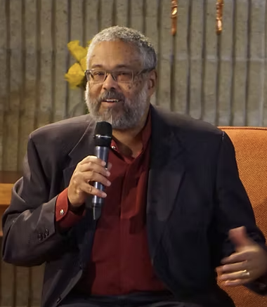 Black man with grey hair speaking with a microphone.