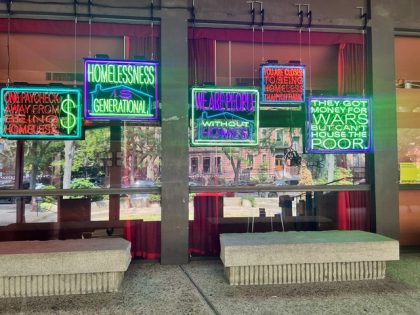 Bright green, orange and purple newon signs in a window with sayings.