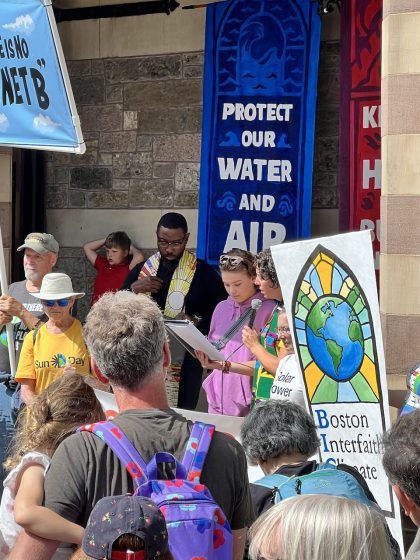 A crowd gathering in front of banners to Protect the environment with bright colored banners