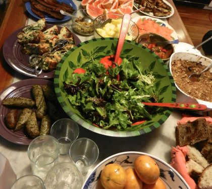 A selection of food on a table with a green salad in the central location